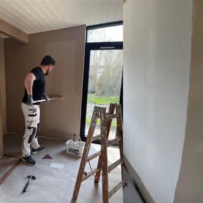 Maler udfører indendørs malerarbejde med rulle på væg i bolig i Slagelse